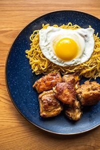 Garlic noodles with glazed baby back ribs and a fried egg